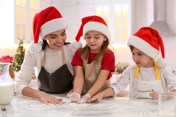 Mother with her cute little children making Christmas cookies in kitchen