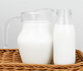A jug and bottle of fresh milk glass on wooden basket background.Raw milk is high in calcium and protein to drink for all ages..Milk consumption nutritious and healthy dairy products concept.