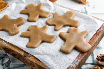 Fototapeta na wymiar Making homemade Christmas cookies. Dough for gingerbread man on wooden board, closeup
