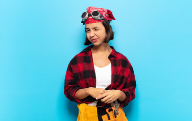 young latin woman looking happy and friendly, smiling and winking an eye at you with a positive...