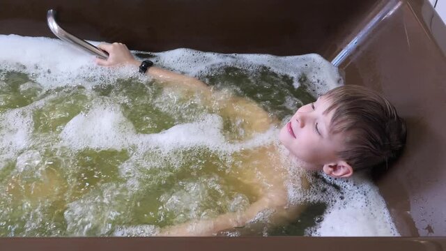 boy bathes. medical procedures hydrotherapy mineral water bubble bath 2020