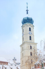 Fototapeta na wymiar The Franciscan Church tower and the famous clock tower in the background, in the city center of Graz, Styria region, Austria, with snow, in winter