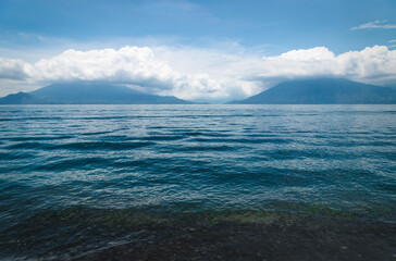 Lake Atitlan with view on the cloudy volcanoes San Pedro and Tiloman at Santa Cruz la Laguna, Guatemala