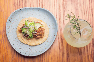 Gourmet Mexican shredded meat tacos on wooden table. Gourmet mexican food. Gourmet tacos and gin tonic.