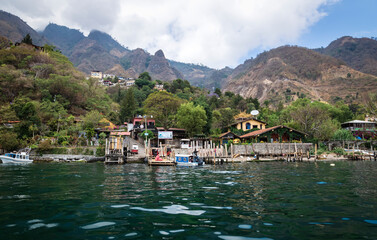 Fototapeta na wymiar View from lake Atitlan to the coast with boat docks of the mountain village Santa Cruz la Laguna, Guatemala