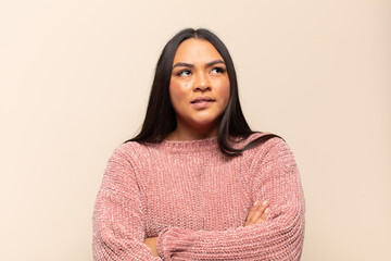 young latin woman doubting or thinking, biting lip and feeling insecure and nervous, looking to...
