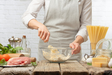 Professional chef in white uniform mix ingredients into glass bowl for preparing dough. Backstage of cooking pasta carbonara. Traditional italian dish on white background. Cooking process concept.