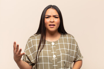 young latin woman looking angry, annoyed and frustrated screaming wtf or what’s wrong with you