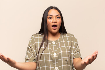 young latin woman open-mouthed and amazed, shocked and astonished with an unbelievable surprise