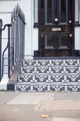Black and white tiles on the stairs of a white British house