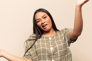 young latin woman shrugging with a dumb, crazy, confused, puzzled expression, feeling annoyed and...