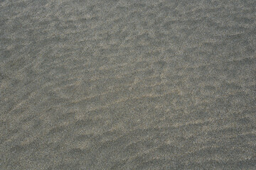 Rippled wet sand in shades of gray as a nature background

