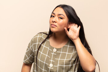 young latin woman looking serious and curious, listening, trying to hear a secret conversation or...