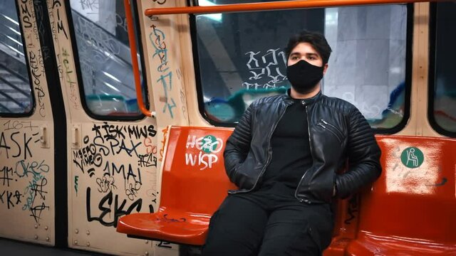 A caucasian man with beard in black medical mask in subway with painted interior, opening doors