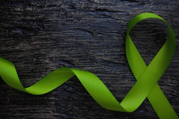 Top view of lime green color ribbon on dark background. Non-hodgkin lymphoma cancer, lyme disease, muscular dystrophy and postpartum depression awareness concept.