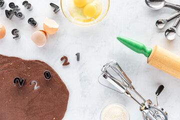 Top down view of a baking scene with baking utensils, ingredients and number cookie cutters using 2021.