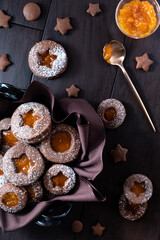 Obraz na płótnie Canvas Top down view of a decorative bowl of chocolate Linzer cookies with apricot jam against a dark background.