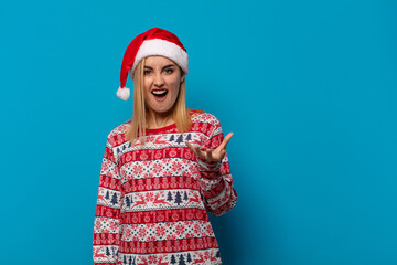 blonde woman with santa hat looking angry, annoyed and frustrated screaming wtf or what’s wrong...