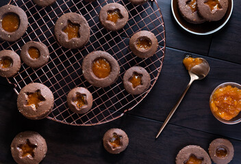 Top down view of chocolate Linzer cookies with apricot preserves on a copper cooling rack.