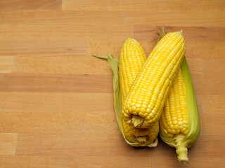 Corns and corn on the cop isolated on wooden table with copy space