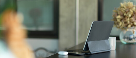 Portable workspace with digital tablet, smartphone and flower vase on black desk