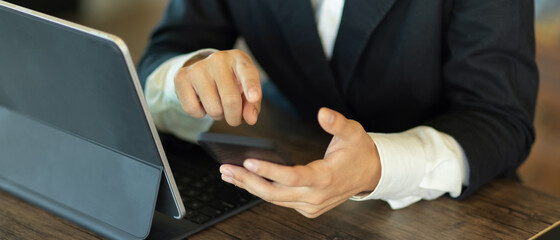 Obraz premium Businesswoman hands using smartphone while working with tablet in office room