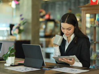 Businesswoman take a coffee break while reading paperwork in cafe