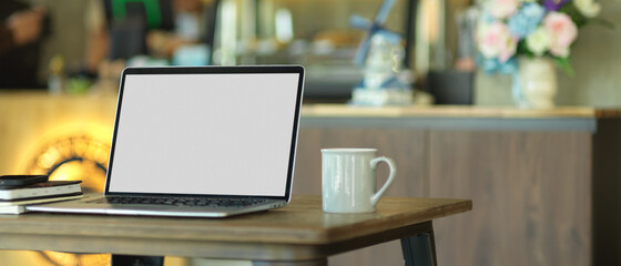 Portable workspace with laptop, notebooks and coffee mug in cafe