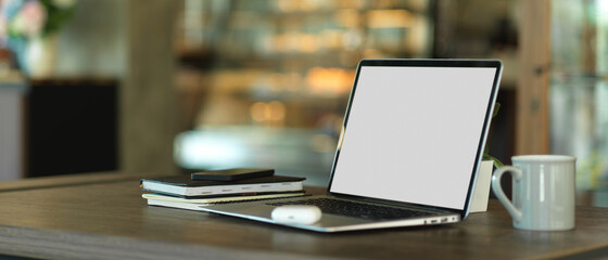 Worktable with laptop, notebooks and coffee mug in office room