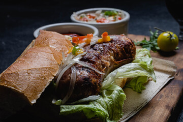 primer plano de choripan comida tipica y tradicional de argentina sandwich de pan con chorizo de cerdo con condimentos salsa criolla lechuga cebolla pimiento morron tomate mayonesa kechup y moztaza