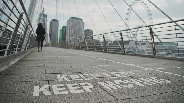 Coronavirus Covid-19 information sign encouraging social distancing in Central London at Jubilee Bridges at South Bank, showing people having to obey 2m social distance rule in England, Europe