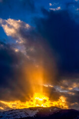 Fototapeta na wymiar Sunset with sun rays, dramatic sky, mountain