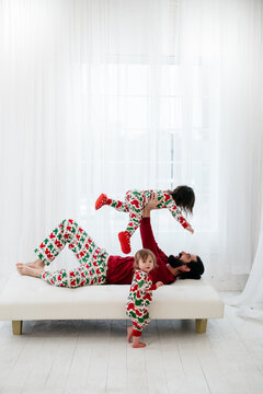 Family Portrait Of Father And Two Children Wearing Matching Pajamas On Christmas In A White Studio Room 