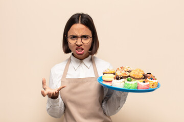 young latin woman looking angry, annoyed and frustrated screaming wtf or what’s wrong with you