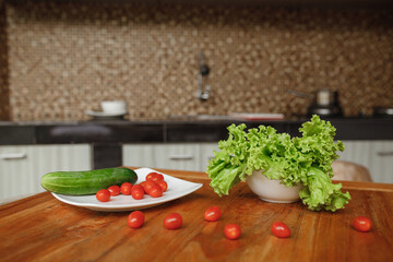 Fresh vegetables - cherry tomatoes, lettuce and cucumber on the plate  at home kitchen. The concept of vegeterian food