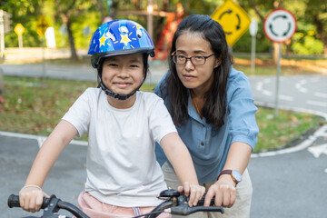 Obraz premium Mother teaching her daughter to ride bicycle in park. Family outdoor on bike ride.