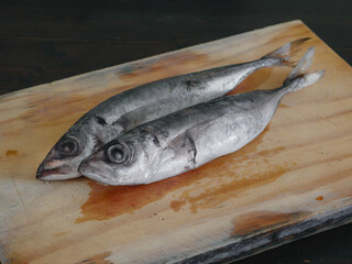 Two raw mackerels on a wooden board