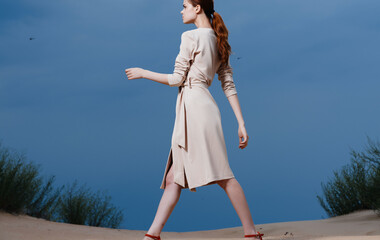 pretty woman in dress affects nature sand blue sky clouds