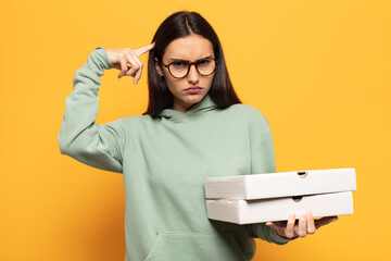 young latin woman feeling confused and puzzled, showing you are insane, crazy or out of your mind