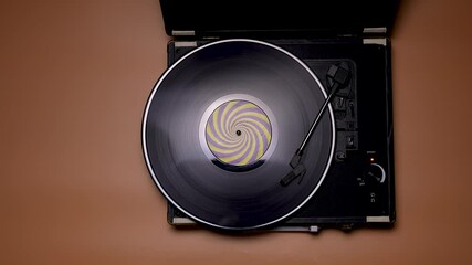 The man shifts the needle on the vinyl record. Top view of male hands and vintage turntable on brown table background. Retro concept. Slow motion. Close up.