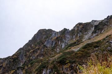 Rocky terrain and yellow grassland in early autumn at Senjojiki Cirque in Nagano Prefecture, Japan.