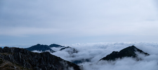 Obraz na płótnie Canvas Panoramic view of Kiso Mountains Range engulfed in thick clouds in early autumn at Senjojiki Cirque in Nagano Prefecture, Japan.