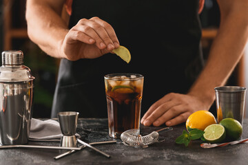 Barman making Cuba Libre cocktail with lime and ice