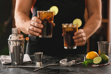 Barman making Cuba Libre cocktail with lime and ice