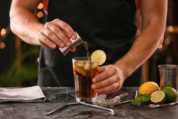 Barman making Cuba Libre cocktail with lime and ice