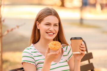 Beautiful young woman with coffee and sweet donut outdoors