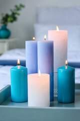 Tray with burning candles in interior of bedroom, closeup