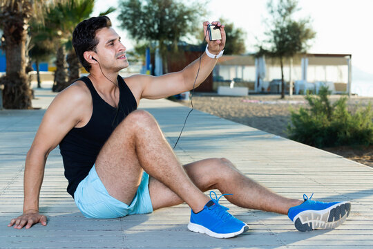 Smiling happy athletic man making selfie during break in workout outdoors