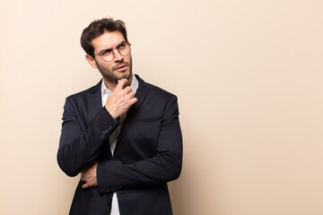 young handsome man thinking, feeling doubtful and confused, with different options, wondering which...