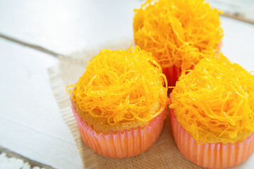 High angle view a group of mamon cake with golden thread topping on a a white wooden table with blank for copy space.